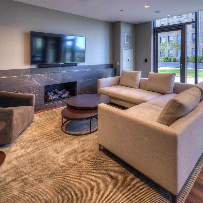 Intimate lounge with tan sectional couch, tv, and fireplace