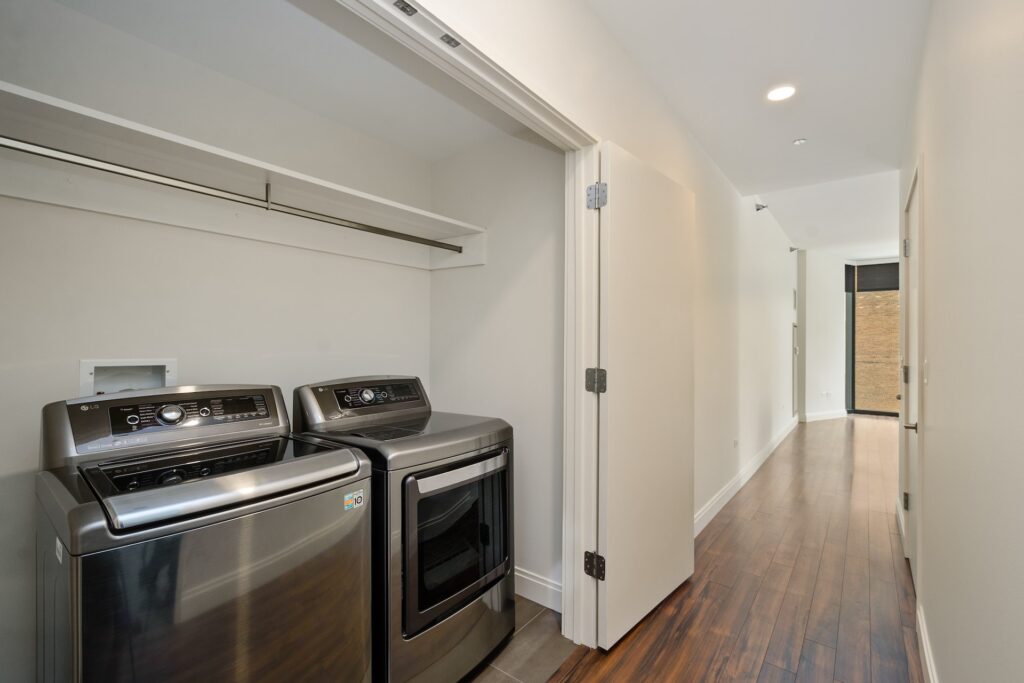 View of High-End In-Unit Washer and Dryer and hallway with wood floors