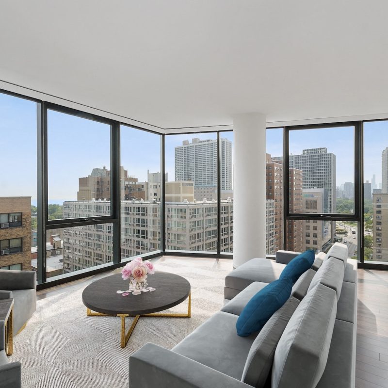 Beautiful apartment living room with gray couch, floor to ceiling windows and skyline view